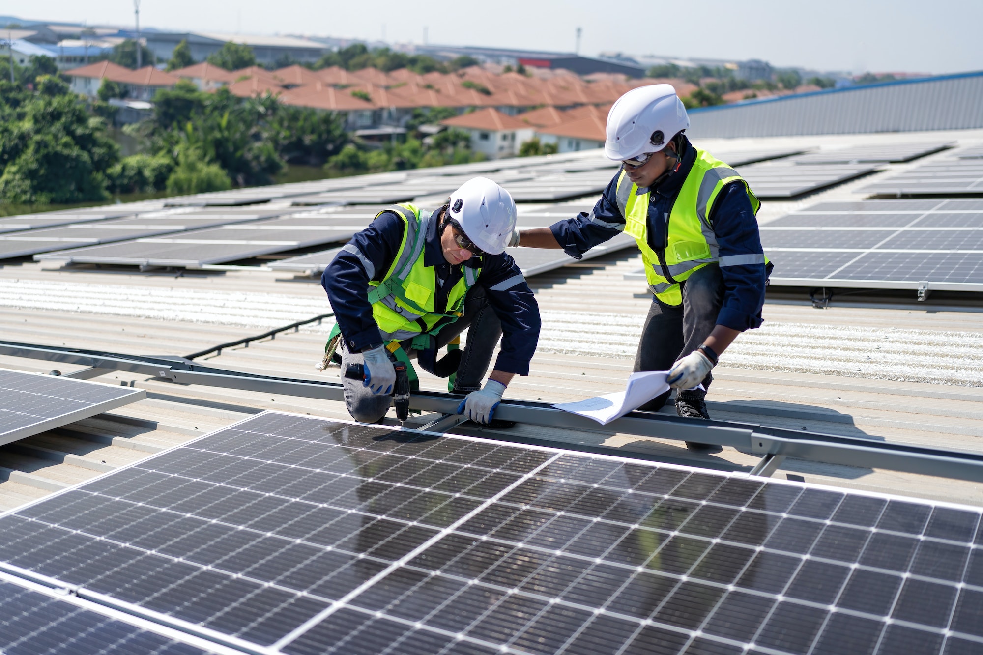 engineer-on-rooftop-kneeling-next-to-solar-panels-photo-voltaic-check-drawing-for-good-installation.jpg