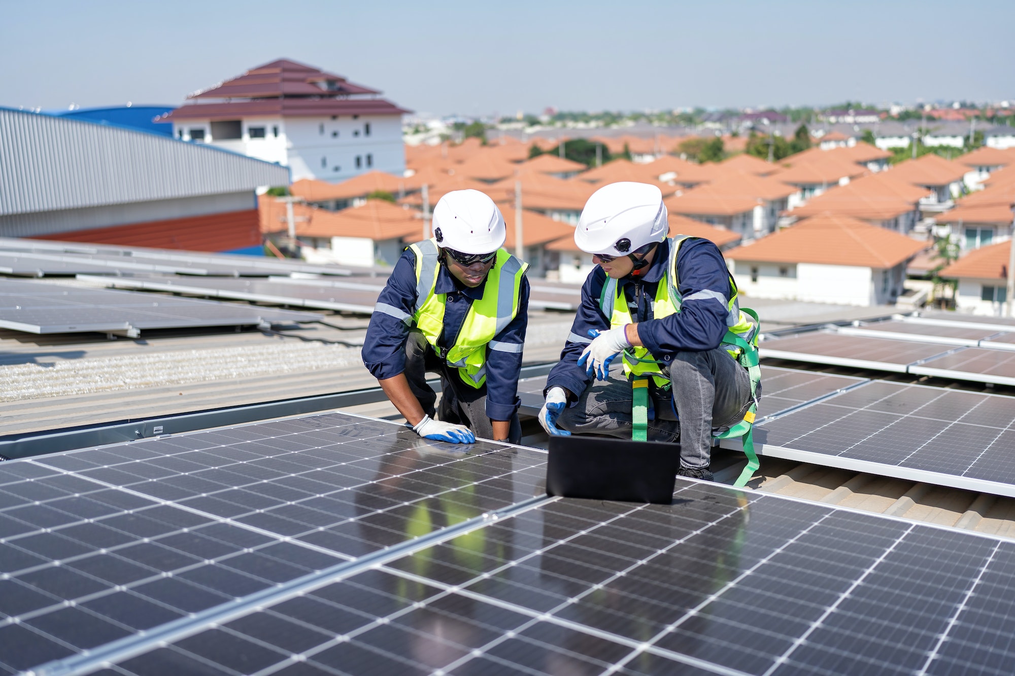 engineer-on-rooftop-kneeling-next-to-solar-panels-photo-voltaic-check-laptop-for-good-installation.jpg
