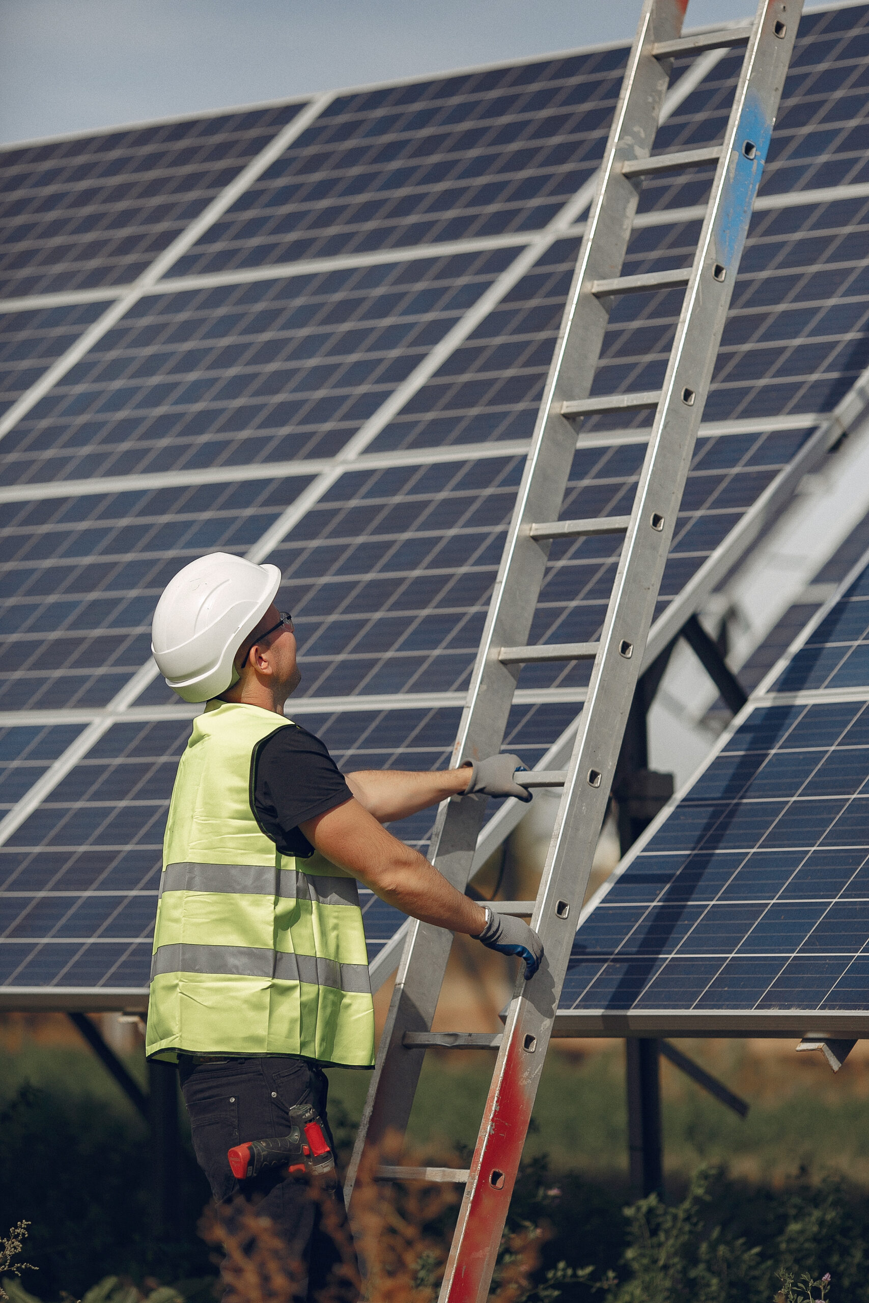 Engineer in a white helmet. Man near solar panel. Worker with a ladder